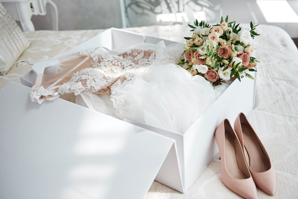 Hochzeitskleid verpackt in weißen Karton mit Schuhen und Blumenstrauß