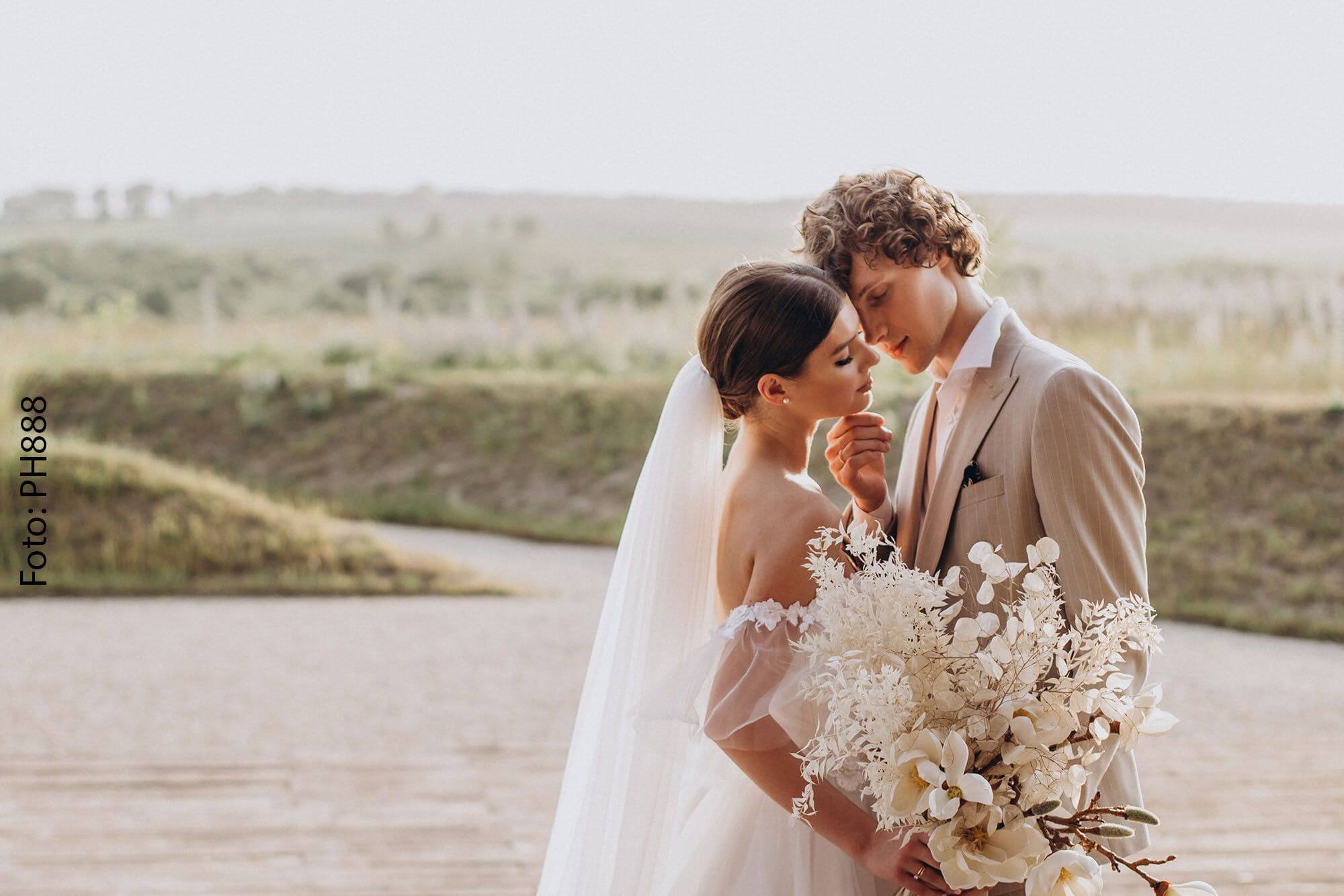 Brautpaar umgeben von einer Naturkulisse, mit Blumenstrauß in der Hand