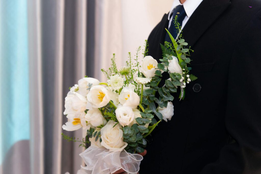 A man in a suit holding a beautiful bouquet of white flowers, perfect for weddings.