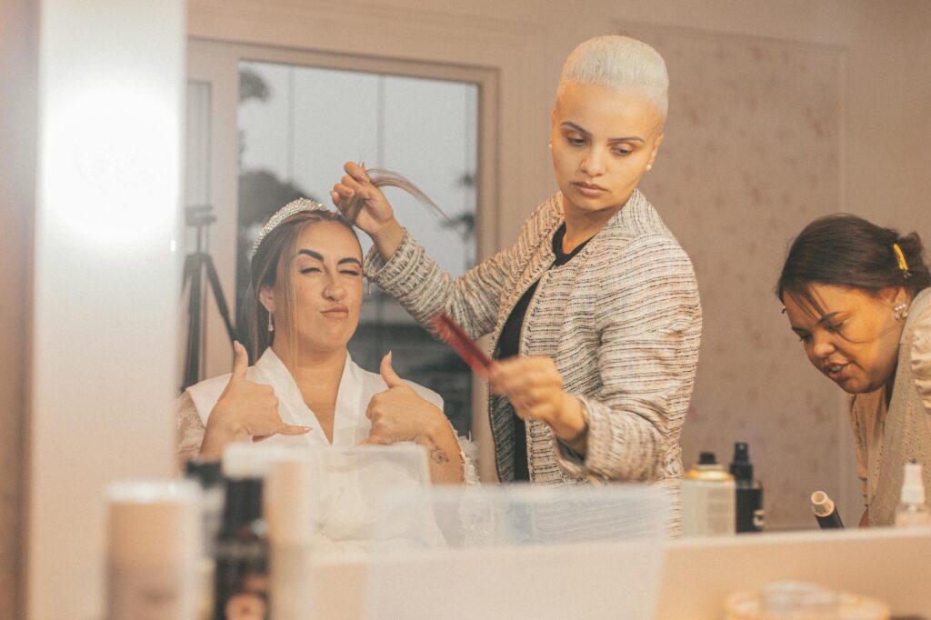 Braut wird von professionellen Stylist:innen vorbereitet – elegante Hochzeitsfrisur mit Charme.