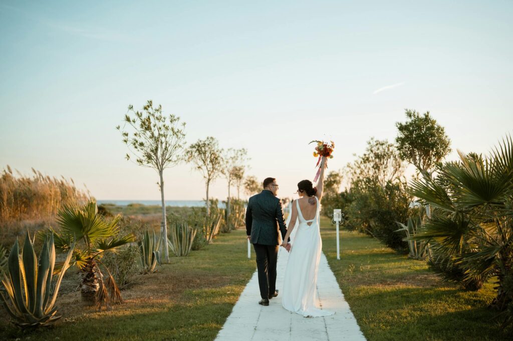 Brautpaar im Freien – Braut hält ihren Strauß mit weißen Blumen im Sonnenlicht.